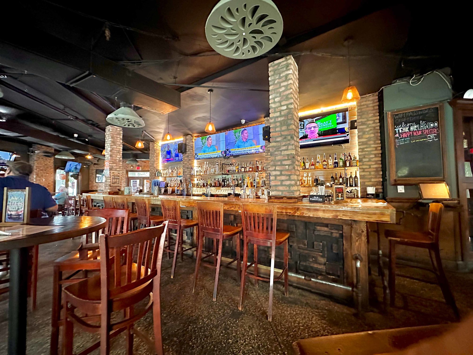 high stools with bar filled with alcohol bottles and brick columns